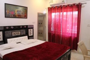 a bedroom with a bed with a red curtain at Hotel Sunset in Orchha