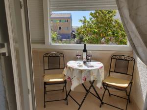 a table with two chairs and a table with wine glasses at Apartment LANA Kaštel Stari in Kaštela