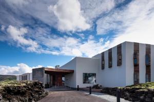 a white building on a hill with a cloudy sky at The Retreat at Blue Lagoon Iceland in Grindavík