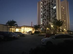 a parking lot with cars parked in front of a tall building at Cozy Staycation at Eastbay Residences in Manila