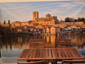 two benches sitting in the water in front of a city at APARTAMENTOS OASIS in Zamora