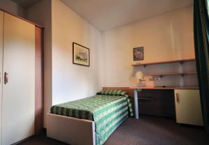 a small bedroom with a bed and a desk at B&B Villa Ursula in Moena