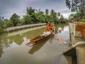 a man is rowing a boat on a river at บ้านกรนรา Baan Kornnara in Amphawa