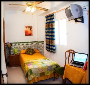 1 dormitorio con cama y mesa con ordenador portátil en Hostal Estación, en Almería