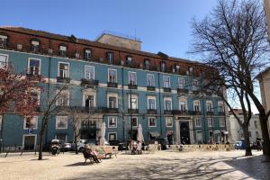 un gran edificio azul con gente sentada frente a él en Sunny 3BDR Apartment in Graça by LovelyStay, en Lisboa