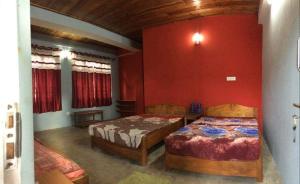 two beds in a room with red walls at Temi Kothi Homestay in Temi