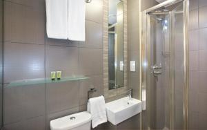 
a bathroom with a toilet, sink, and shower at Eden Plaza Kensington in London
