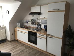 una pequeña cocina con armarios blancos y nevera. en Ferienwohnungen Kutscherschänke, en Bad Zwischenahn