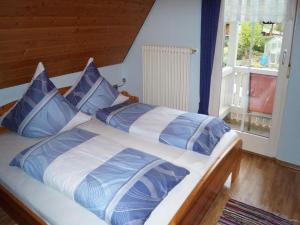 a bed with blue and white pillows and a window at Klausseppenhof in Oberwolfach
