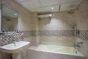 a bathroom with a sink and a tub and a mirror at HOTEL THE CAPITAL LTD. in Dhaka