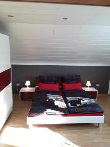 a bedroom with a large bed with red pillows at Ferienwohnung Wagner in Zweibrücken