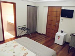 Habitación con cama, TV y silla. en Hotel Acrópolis en Santana do Livramento