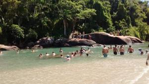 a group of people in the water at a beach at Aldeia Itamambuca Chalé Camping Ubatuba in Ubatuba