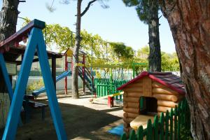 a playground with a wooden house and a slide at Lagonisi Beach Resort in Ormos Panagias