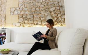 a woman sitting on a couch reading a book at Marton Hotel Valldemossa in Valldemossa