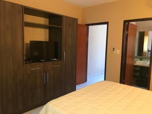a bedroom with a large wooden cabinet with a flat screen tv at Mandala in Luque