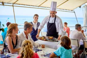 un chef que sirve comida a un grupo de personas en una mesa en Forte Village Resort - Le Palme, en Santa Margherita di Pula