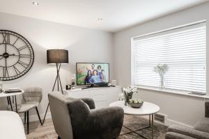 a living room with a clock and a tv at Tailored Stays - Central Cambridge Studios, Free Parking in Cambridge