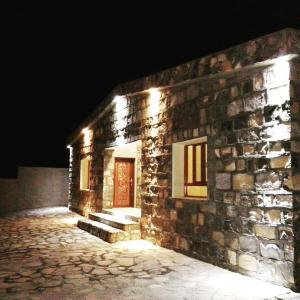 Jabal Shams Mountain Rest House في Al Hūb: مبنى حجري بباب احمر بالليل