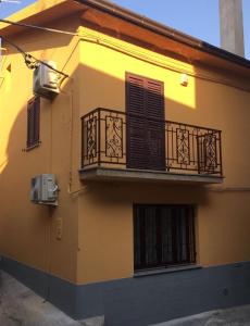 Edificio amarillo con balcón y ventanas en Casa vacanze One en Frascineto