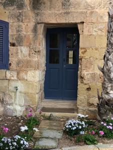 Ta Skorba Farmhouse Mgarr في Mġarr: باب أزرق على مبنى حجري وبه زهور