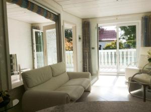 ein Wohnzimmer mit einem Sofa und einem Balkon in der Unterkunft Ferien-Appartement am Schloßsee in Salem