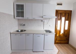 a kitchen with white cabinets and a sink at Apartment Anastasija in Doboj