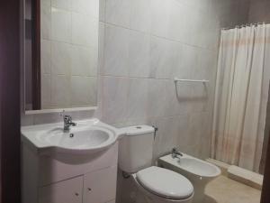 a white bathroom with a toilet and a sink at Residência Livramento in Velas +23 photos