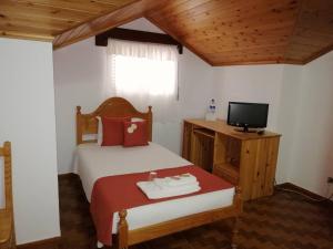 ein Schlafzimmer mit einem Bett und einem TV in einem Zimmer in der Unterkunft Residência Livramento in Velas