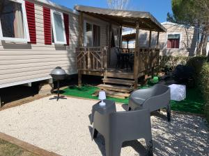 维亚斯Mobilhome Vias plage dans Camping的房屋设有1个带椅子和桌子的甲板