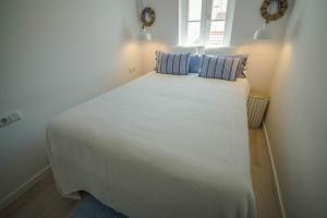 uma grande cama branca com duas almofadas em Gil Vicente House na Nazaré