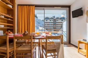 a dining room with a table and a large window at Résidence Pierre & Vacances le Moriond in Courchevel