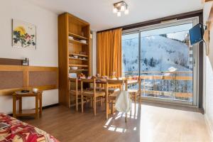 a room with a dining table and a large window at Résidence Pierre & Vacances le Moriond in Courchevel