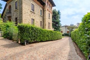 a brick building with a hedge next to a brick road at Ramé Suites in Bergamo