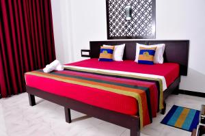 ein Schlafzimmer mit einem großen Bett mit bunten Decken und Kissen in der Unterkunft Myr-o Homestay in Anuradhapura