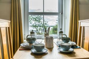 a wooden table with plates and glasses and a window at The Old School House B&B in Gairloch