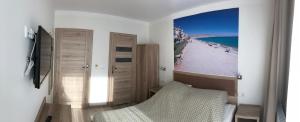 una camera con letto e una foto di una spiaggia di Pokoje Gościnne - Port a Międzywodzie