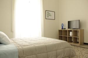 a white bedroom with a bed and a television at Dimora del sole in Catania
