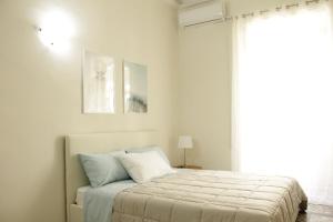 a white bedroom with a bed and a window at Dimora del sole in Catania