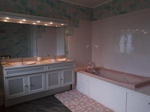 ein Badezimmer mit zwei Waschbecken, einer Badewanne und einem großen Spiegel in der Unterkunft Chambre du Nouvion in Le Nouvion-en-Thiérache