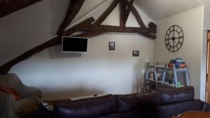 sala de estar con sofá de cuero y TV en Chambre du Nouvion en Le Nouvion-en-Thiérache