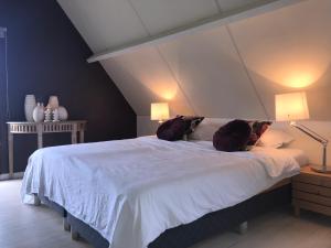 a bedroom with a large white bed with two lamps at Vitamine D in Koksijde