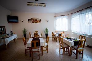 a dining room with tables and chairs and windows at Hotelik - Modlin Airport in Nowy Dwór Mazowiecki