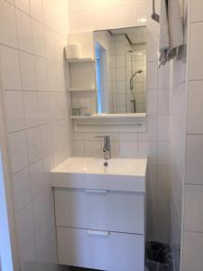 La salle de bains blanche est pourvue d'un lavabo et d'un miroir. dans l'établissement Pension Zandvoort aan Zee, à Zandvoort