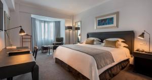 a hotel room with a large bed and a desk at Hotel Avenida in Maputo