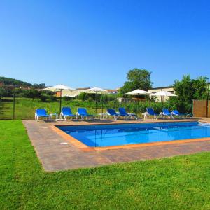 a swimming pool with blue chairs and umbrellas at Hostal Can Bassalis in Pals