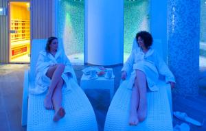 two women sitting on blue chairs in a room at Hotel Terme Capasso in Contursi