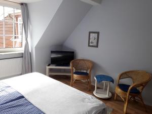 a bedroom with a bed and two chairs and a television at Pension Norddeicher Straße in Norden