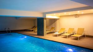 a pool in a room with chairs and a table at Hotel Aazaert by WP Hotels in Blankenberge
