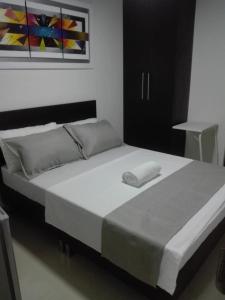 a bedroom with a large bed with white sheets at Hotel Girón Plaza in Girón